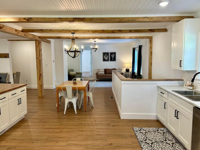 kitchen with light hardwood / wood-style flooring, hanging light fixtures, sink, and white cabinets