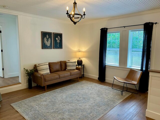 living area featuring crown molding, baseboards, wood finished floors, and a chandelier