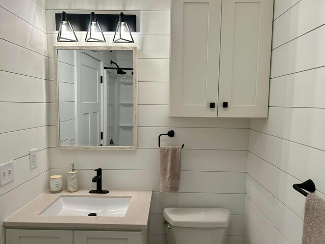 bathroom with vanity, a shower, toilet, and tile walls