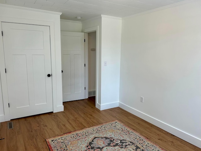 unfurnished bedroom with baseboards, light wood-style floors, crown molding, and visible vents