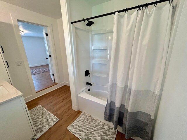 bathroom with baseboards, wood finished floors, and shower / tub combo with curtain