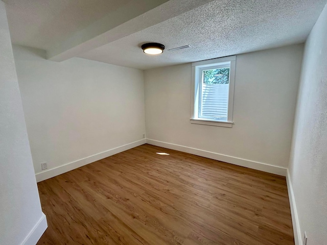 spare room with baseboards, a textured ceiling, and wood finished floors