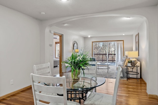 dining room featuring wood-type flooring and a textured ceiling