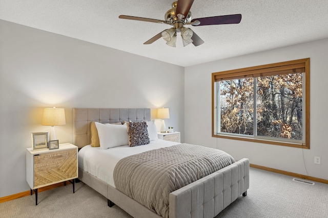 bedroom with ceiling fan, carpet flooring, and a textured ceiling