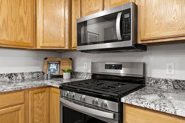 kitchen with light stone counters and appliances with stainless steel finishes