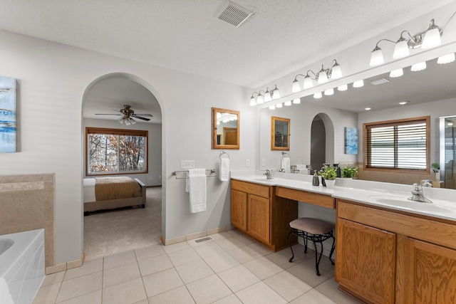 bathroom featuring a washtub, ceiling fan, vanity, a textured ceiling, and tile patterned floors