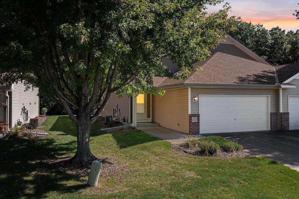 view of front facade with entry steps, brick siding, a lawn, and an attached garage