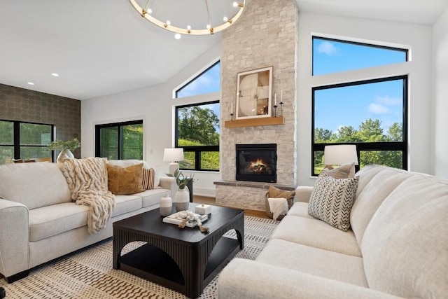 living area featuring recessed lighting, light wood-style flooring, a high ceiling, an inviting chandelier, and a stone fireplace