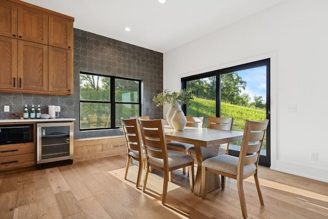 dining room with a wealth of natural light, light wood-type flooring, beverage cooler, and recessed lighting