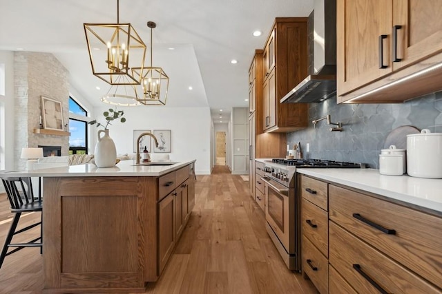 kitchen with a sink, a kitchen breakfast bar, wall chimney range hood, high end stainless steel range oven, and brown cabinetry