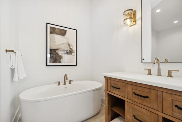 bathroom featuring a freestanding tub, vanity, and recessed lighting