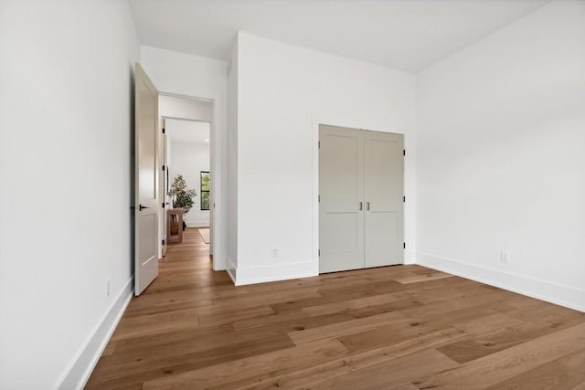 unfurnished bedroom with a closet, baseboards, and wood finished floors