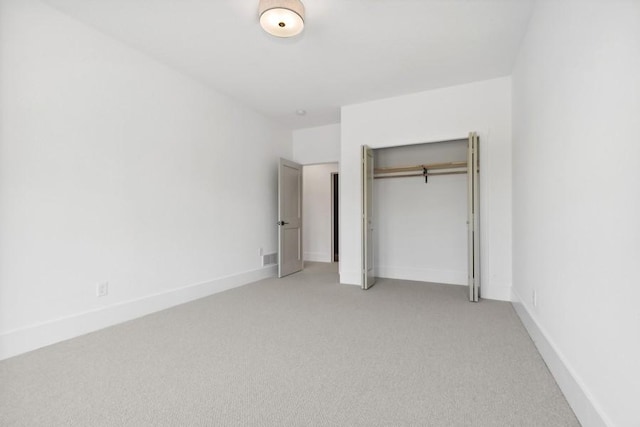 unfurnished bedroom featuring baseboards, a closet, and light colored carpet