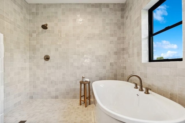 bathroom with a soaking tub, a tile shower, and tile walls