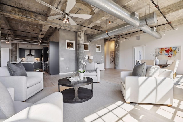 living room featuring light hardwood / wood-style floors, ceiling fan, and a high ceiling