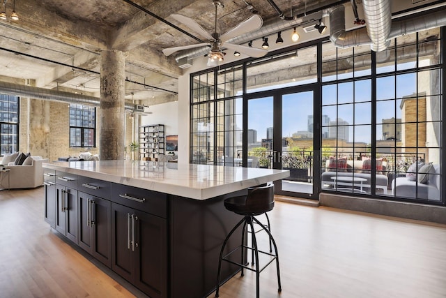 kitchen featuring a breakfast bar area, a high ceiling, a center island, ceiling fan, and light wood-type flooring