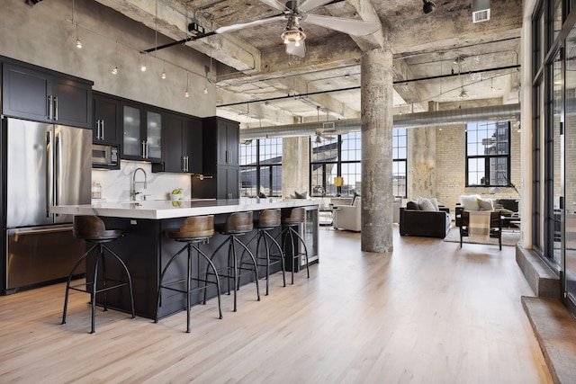 kitchen featuring a breakfast bar, sink, light hardwood / wood-style flooring, appliances with stainless steel finishes, and ceiling fan