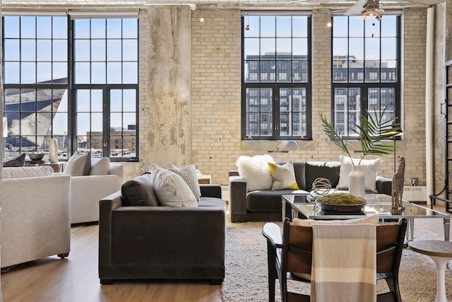 living room featuring brick wall, hardwood / wood-style floors, and plenty of natural light