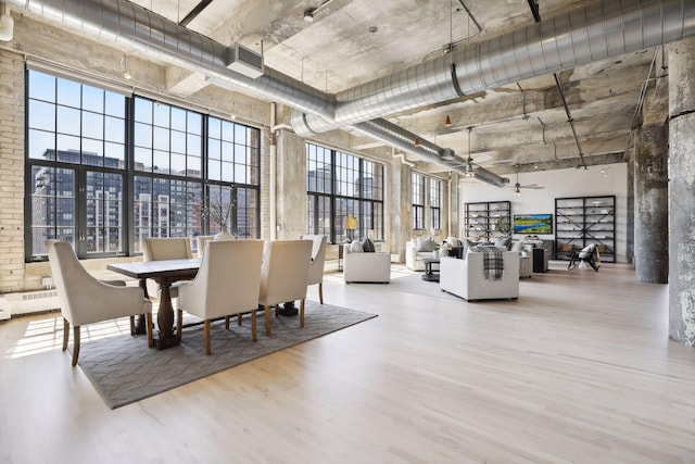 dining area with a towering ceiling and light hardwood / wood-style floors