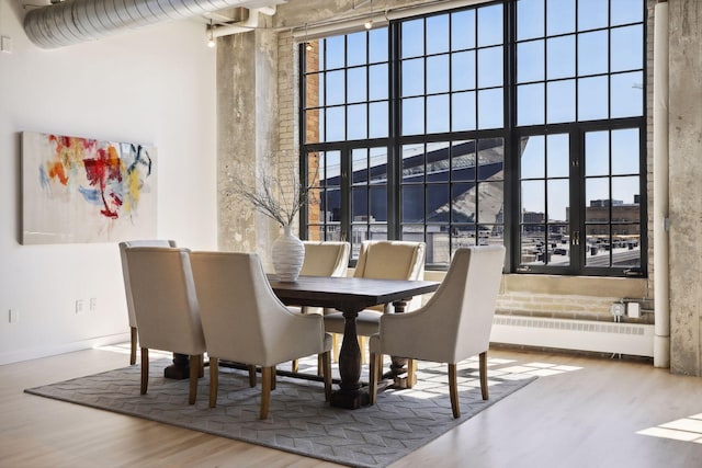 dining area featuring a high ceiling, radiator, and light hardwood / wood-style floors