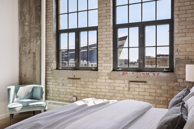 bedroom featuring multiple windows and brick wall