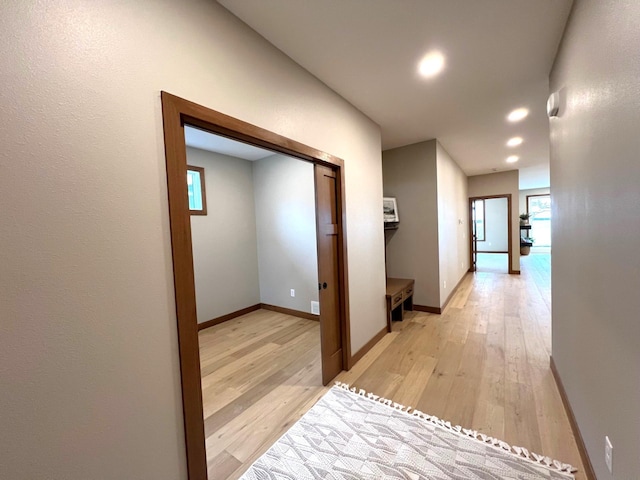 hall with a wealth of natural light and light hardwood / wood-style floors