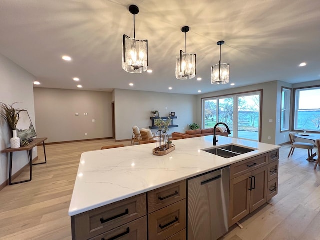 kitchen with light stone counters, sink, decorative light fixtures, and stainless steel dishwasher