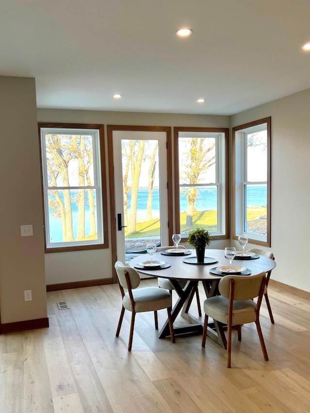 dining space with a water view and light wood-type flooring