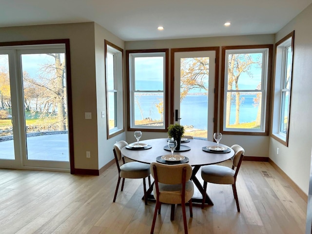 dining space with a water view and light wood-type flooring