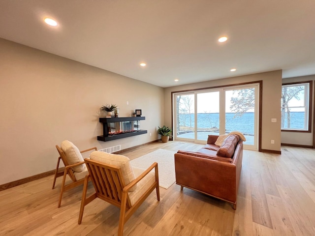 living room with a wealth of natural light, light hardwood / wood-style floors, and a water view