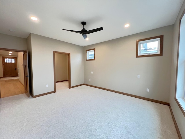 unfurnished bedroom with multiple windows, a walk in closet, and light carpet