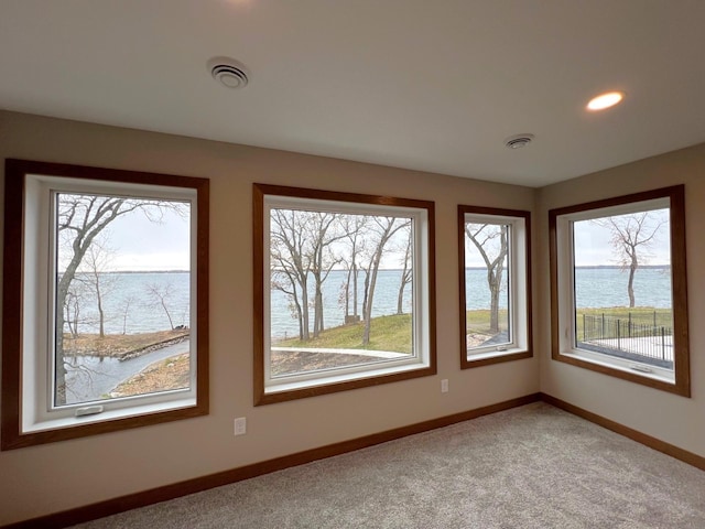 empty room with a water view and carpet flooring