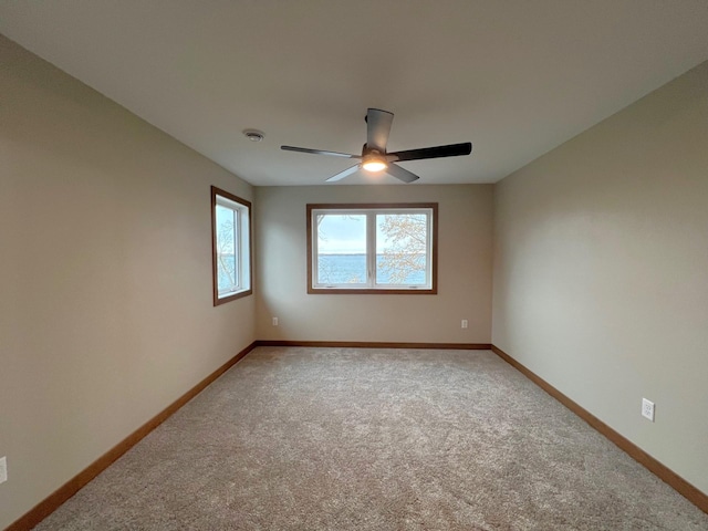 carpeted spare room featuring ceiling fan