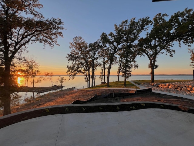 pool at dusk featuring a water view