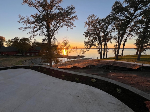 pool at dusk featuring a water view