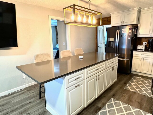 kitchen with a breakfast bar, decorative light fixtures, dark hardwood / wood-style flooring, and a center island