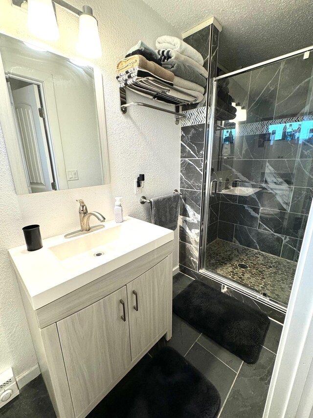 bathroom featuring a shower with door, vanity, and tile patterned flooring