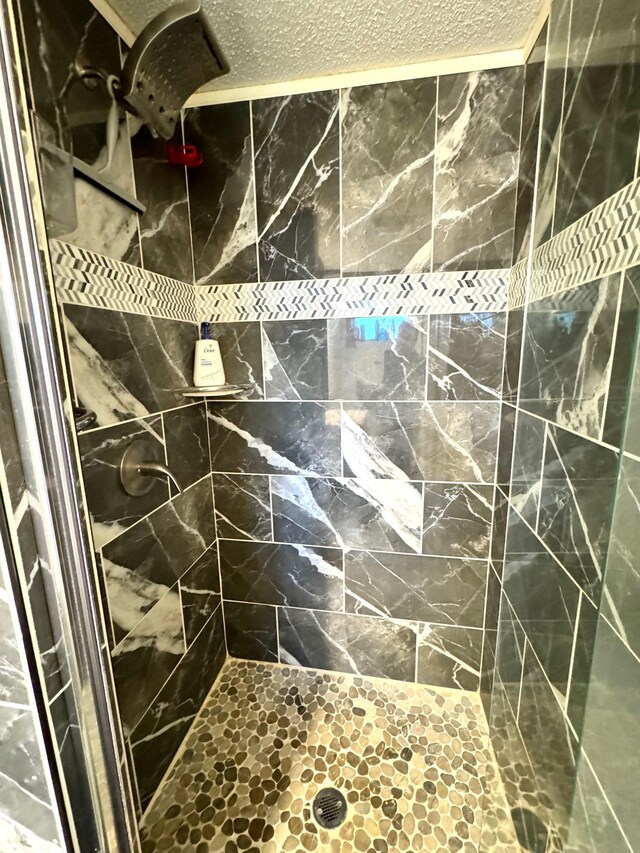 bathroom featuring a tile shower and a textured ceiling