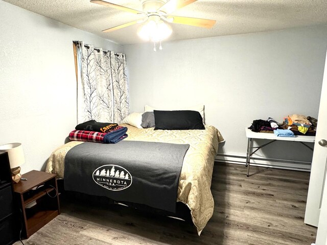 bedroom with hardwood / wood-style flooring, ceiling fan, a baseboard heating unit, and a textured ceiling