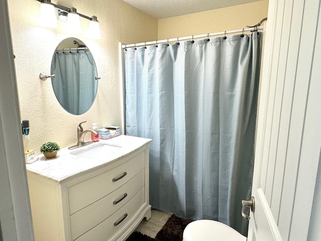 bathroom with vanity, a textured ceiling, and toilet