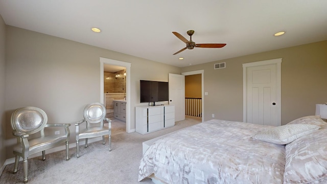 bedroom featuring ceiling fan, ensuite bathroom, and light colored carpet