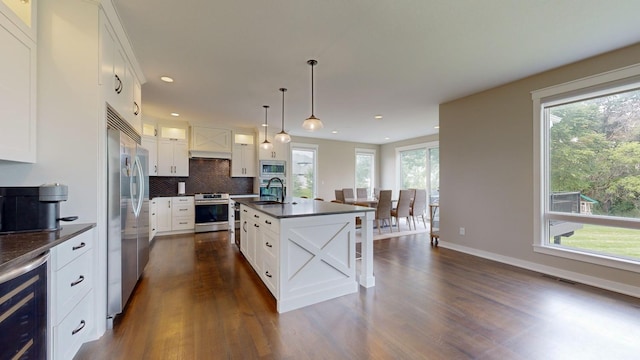 kitchen with white cabinetry, an island with sink, beverage cooler, hanging light fixtures, and stainless steel appliances