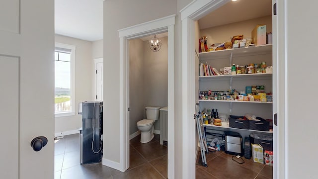 bathroom with tile patterned floors, toilet, and a chandelier