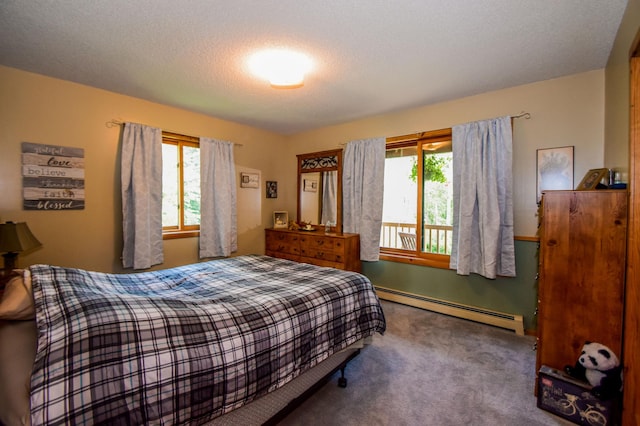 bedroom with a textured ceiling, carpet floors, multiple windows, and a baseboard heating unit