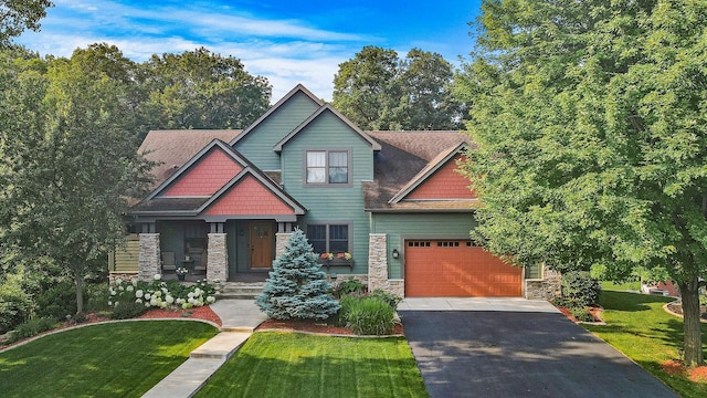 craftsman inspired home with aphalt driveway, stone siding, a garage, and a front yard