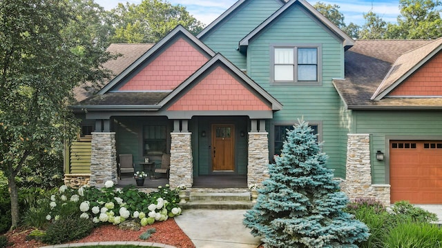 craftsman house featuring a porch, an attached garage, stone siding, and roof with shingles