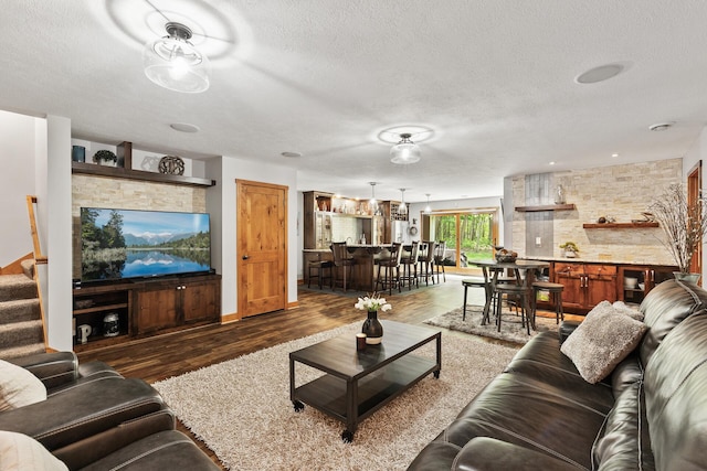 living room featuring stairway, bar area, wood finished floors, and a textured ceiling