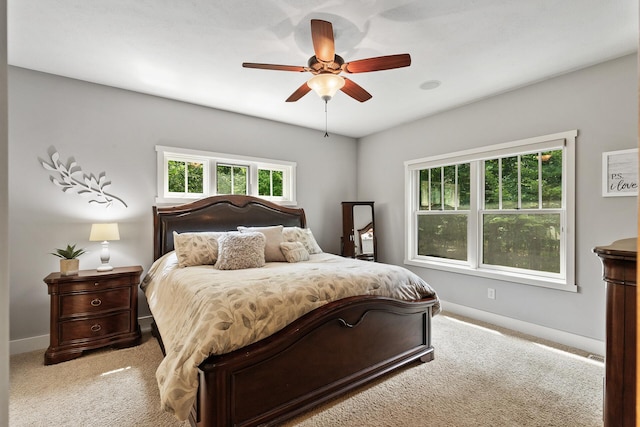 bedroom featuring baseboards, light colored carpet, and a ceiling fan