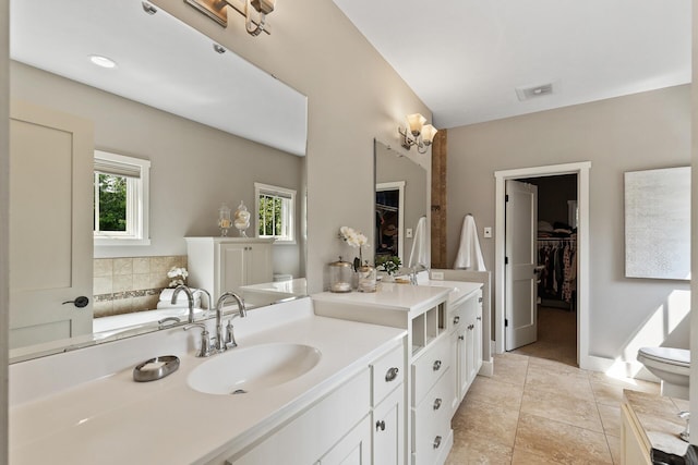 bathroom with visible vents, toilet, vanity, and a walk in closet