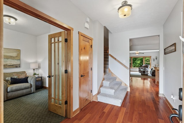 hall with stairs, baseboards, and wood finished floors